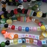 a line-up of colourful beads necklaces with names laying on a white table