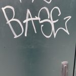 white graffiti on a dark grey electrical box that says hoe base