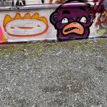 graffiti with a smiling face in orange and yellow paint and a puple frowning face