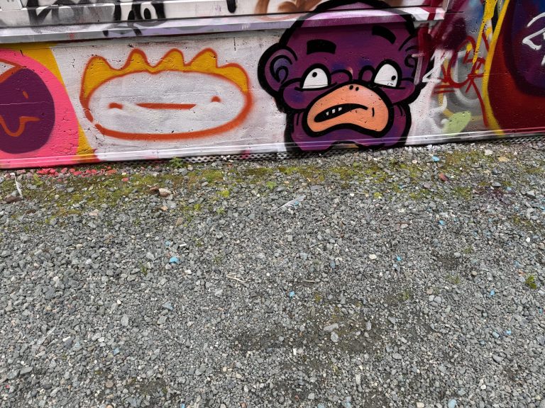 graffiti with a smiling face in orange and yellow paint and a puple frowning face